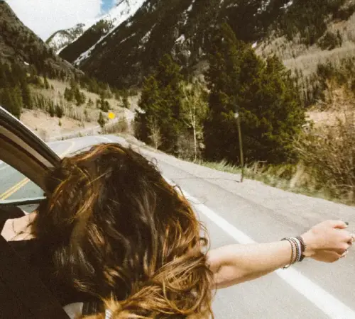 mujer viajando en un auto de copiloto con la cabeza fuera de la ventana | México Ahora Durante las vacaciones de Semana Santa miles de familias salen a carretera para disfrutar de unos días de descanso