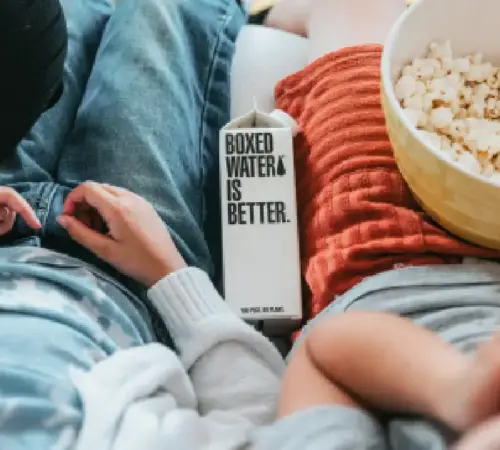 personas sentadas en un sillón con palomitas y botella de agua | México Ahora Con un poco de creatividad es posible convertir estos días en una experiencia igual de placentera