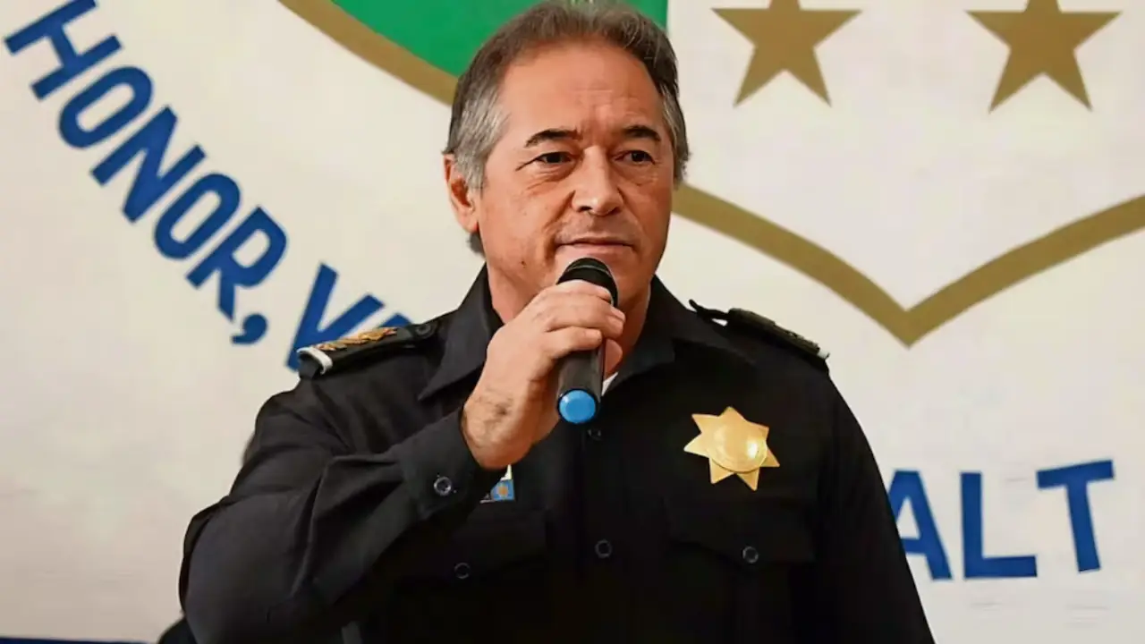 Hernán Bermúdez Requena | México Ahora Male police officer in uniform speaks into a microphone at an event with a gold star badge visible on chest
