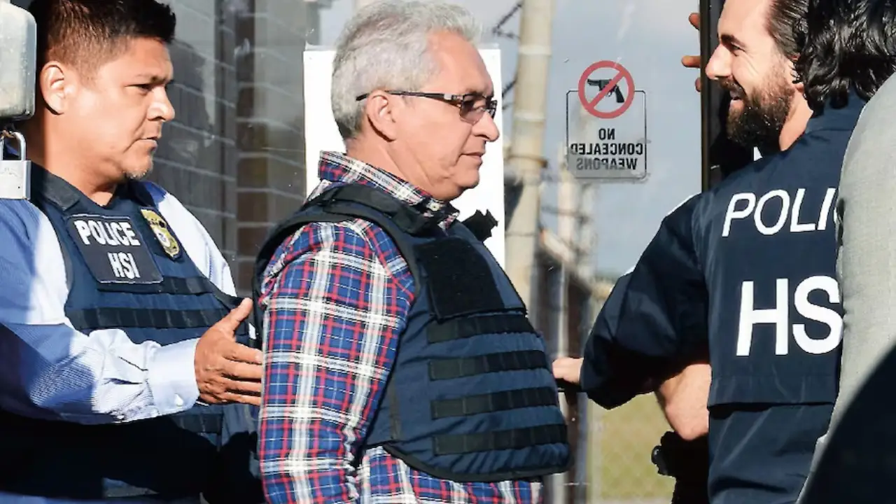 Tomás Yarrington | México Ahora Older man in a plaid shirt is escorted by two police officers wearing HSI vests outside a building
