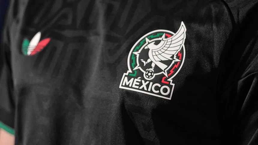 af776cb3-d096-4eb2-98d6-79aff36046dc | México Ahora Black Mexico national soccer team jersey displaying the crest with an eagle and a glowing ball green and red trim visible along the edges