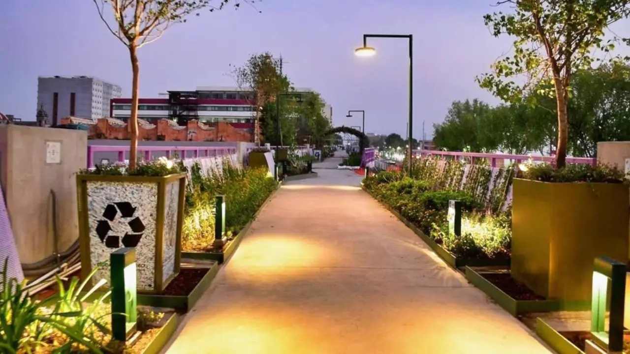 Parque Elevado de Calzada de Tlalpan | México Ahora Evening view of a pedestrian promenade with illuminated path potted plants and modern street lamps flanking the walkway