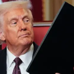 Trump impone aranceles a Canada Trump impone aranceles de 50 a productos de Canadá y escala la tensión comercial en Norteamérica | Man in a dark suit and tie sits holding a large black folder or binder looking to the side in a formal setting