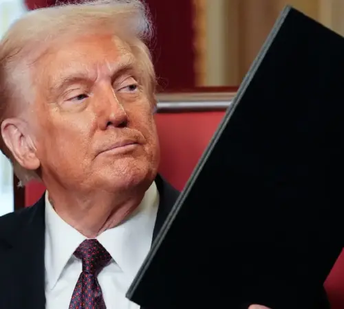 Trump impone aranceles a Canada Trump impone aranceles de 50 a productos de Canadá y escala la tensión comercial en Norteamérica | Man in a dark suit and tie sits holding a large black folder or binder looking to the side in a formal setting