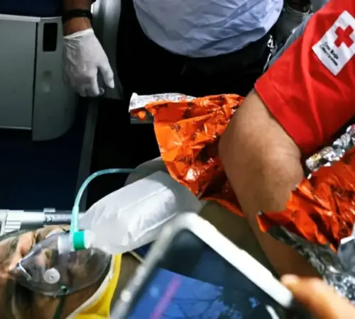 rescatehernangill Tras 100 horas de trabajo rescatan a Hernán en Venezuela con ayuda internacional | Patient on a stretcher wearing an oxygen mask attended by responders with an orange emergency blanket nearby indoors