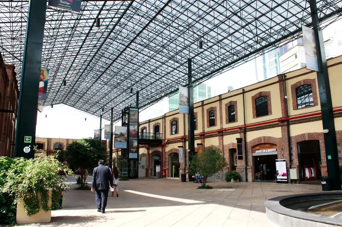 Plaza Loreto Terrenos de Hernán Cortés y que ahora son de Carlos Slim de molinos a plazas comerciales | Open air shopping arcade with a glass lattice roof brick buildings and shoppers strolling among potted plants