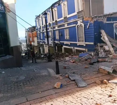 terremotocolombia Terremoto de 74 en Colombia causa daños heridos y dos muertos en Manizales | Street scene after a building collapse with a blue multi story row house and rubble filling the cobblestone street