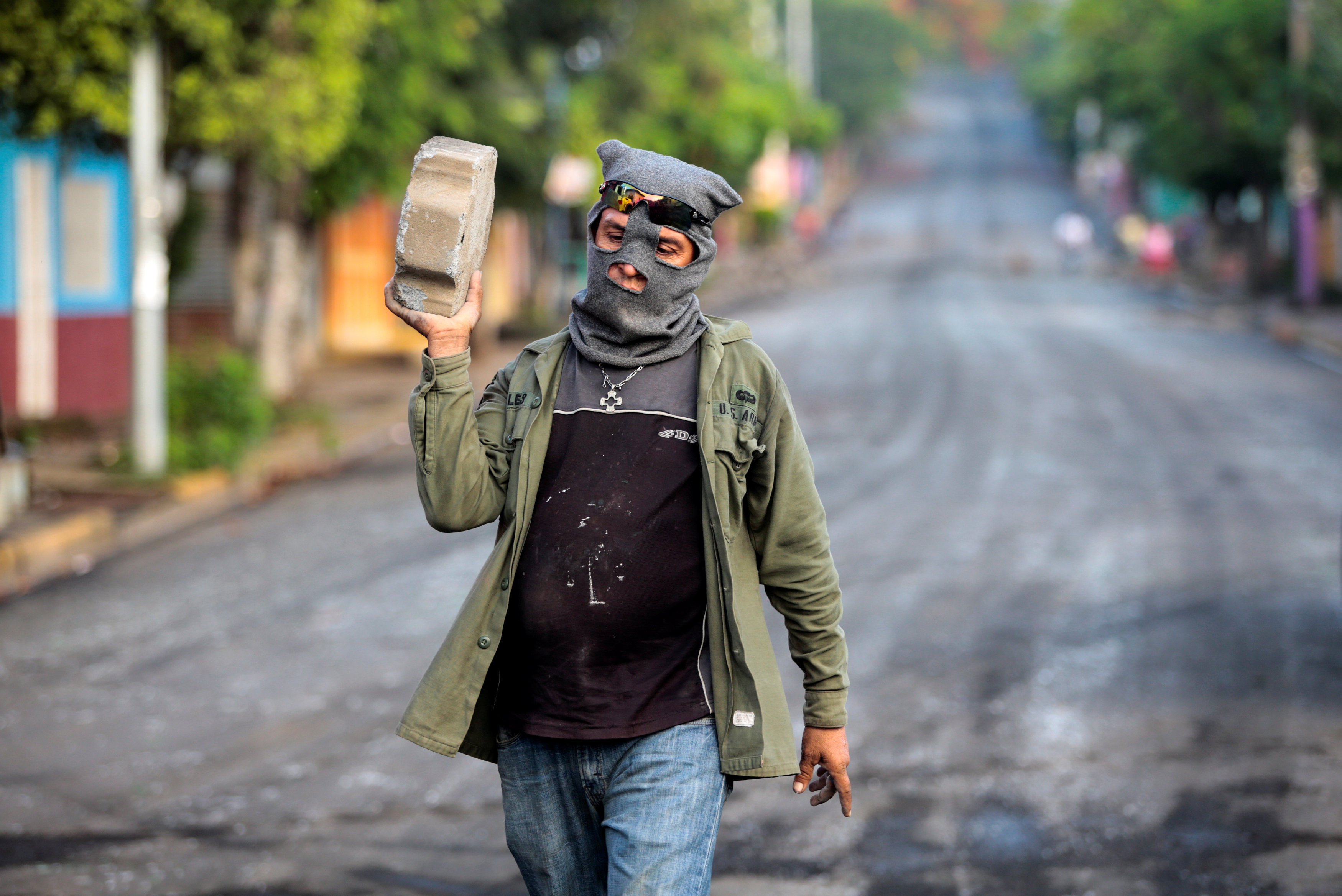 El miembro de una de las fuerzas de choque de Ortega carga una piedra en Monimbo en Masaya, (REUTERS/Oswaldo Rivas)