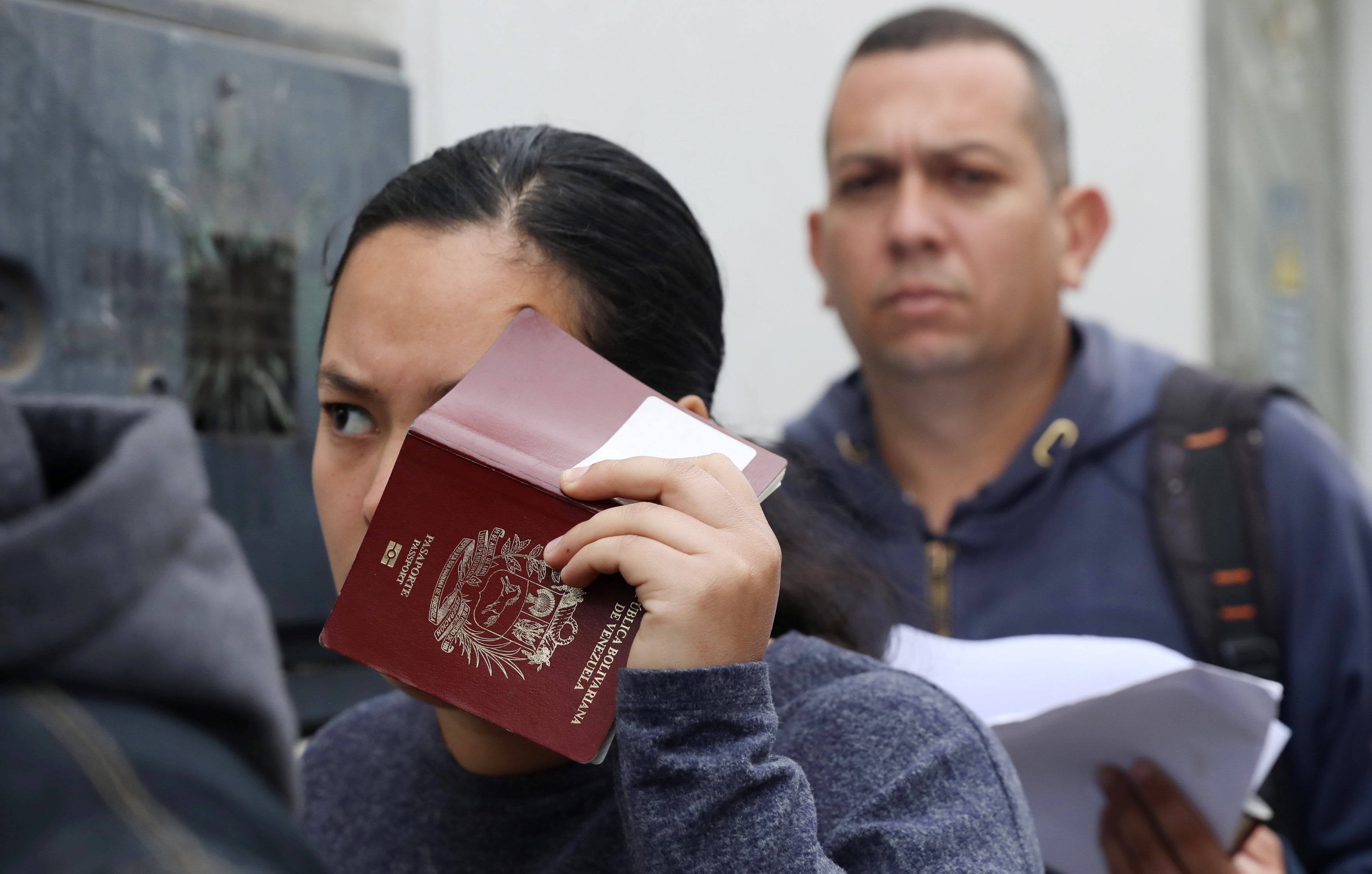 Una inmigrante venezolana tapa su rostro con un pasaporte antes de presentarse ante las autoridades de inmigración peruanas. (REUTERS/Mariana Bazo)