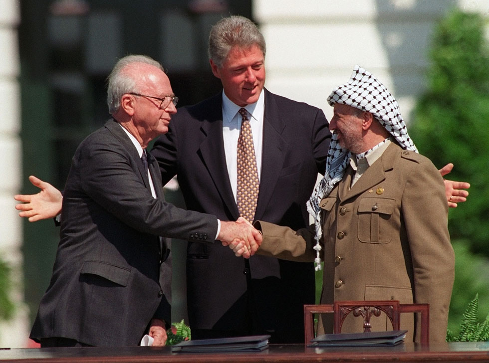 El premier israelí Yitzhak Rabin y el lider de la OLP Yasser Arafat se dan la mano bajo la mirada de Bill Clinton en la ceremonia para la firma de los acuerdos de Oslo el 13 de septiembre de 1993, en Washington (AP Photo/Ron Edmonds)