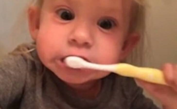 Finge que su cepillo de dientes es eléctrico para imitar a su padre. Su expresión derrite corazones