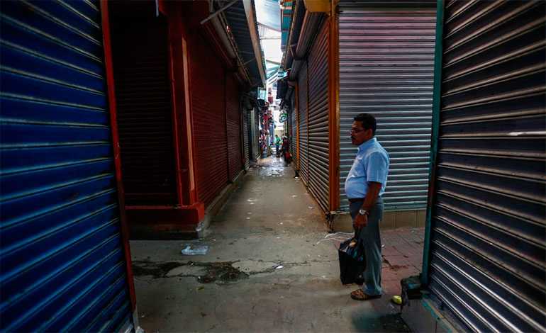 En esta imagen, tomada el 7 de septiembre de 2018, un hombre camina entre las persianas cerradas de los puestos del Mercado Oriental durante un huelga general de 24 horas, en Managua, Nicaragua. En junio, la actividad económica del país había caído un 12,1% en comparación con el año anterior, según el Banco Central. (AP Foto/Alfredo Zúñiga)