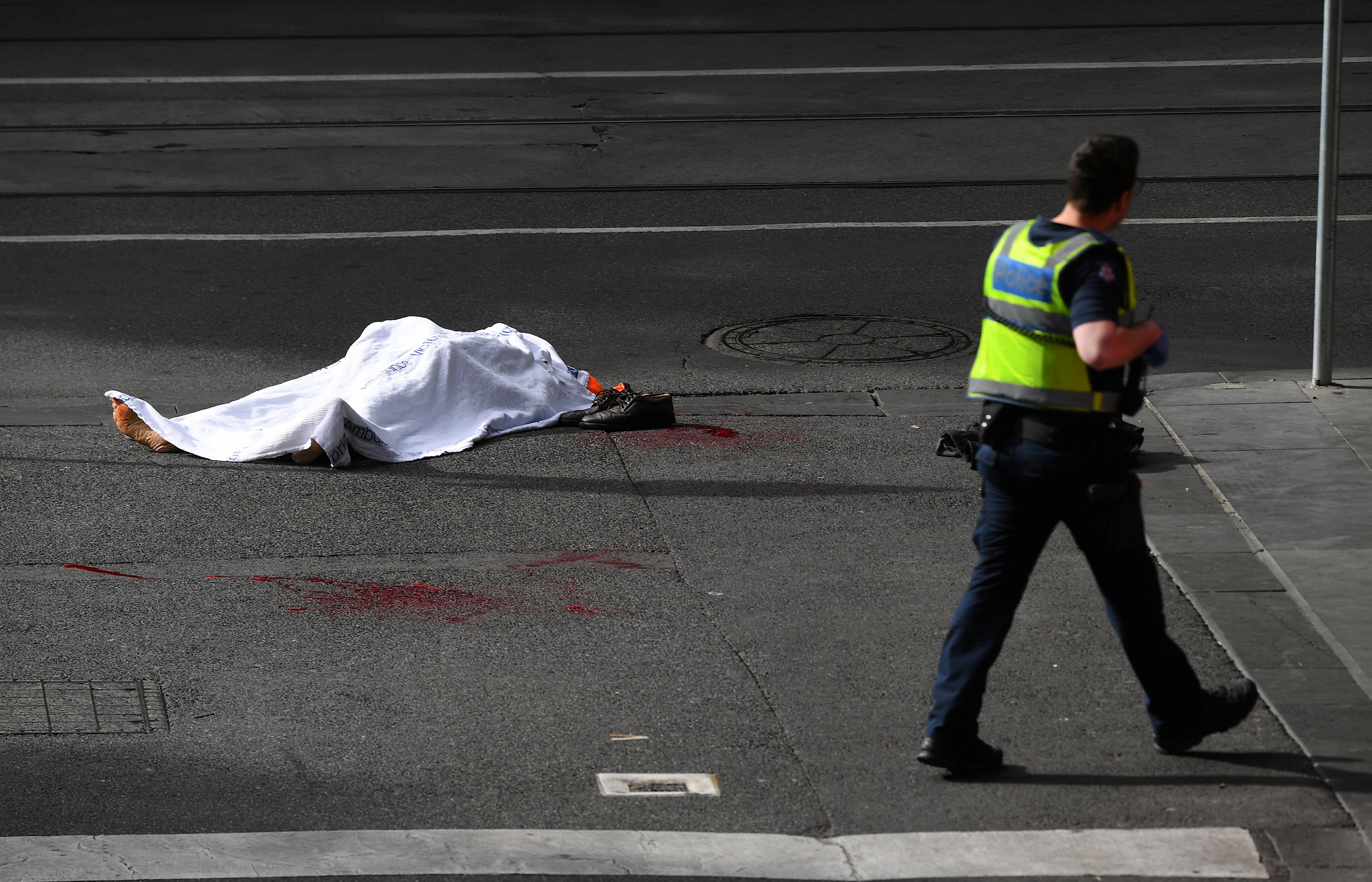 Un policía camina cerca del cuerpo de la víctima mortal del ataque (AAP/James Ross/via REUTERS)