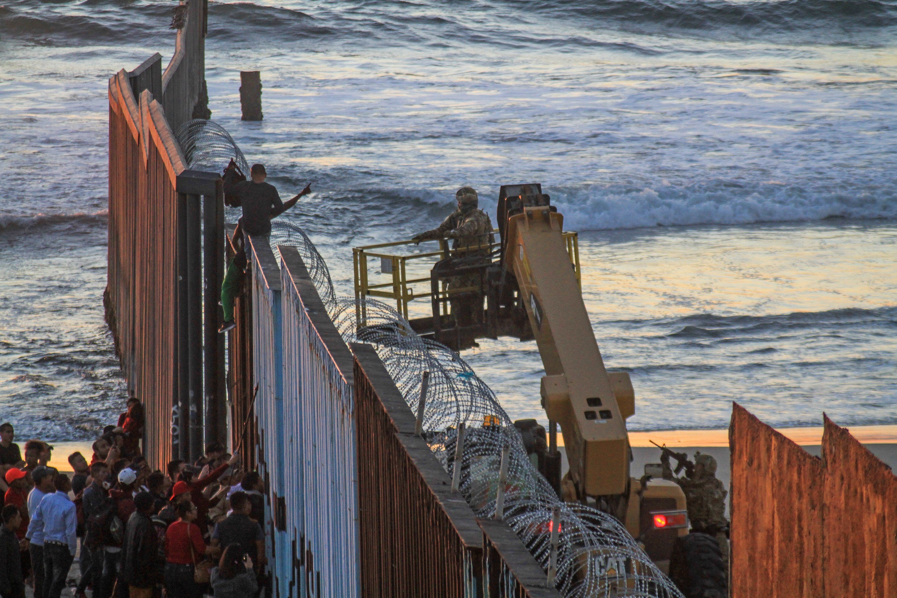 Migrantes de la primera caravana, que salió desde honduras y recorrió el territorio mexicano, comienzan a congregarse en la valla fronteriza de Tijuana. (EFE/Joebeth Terriquez)