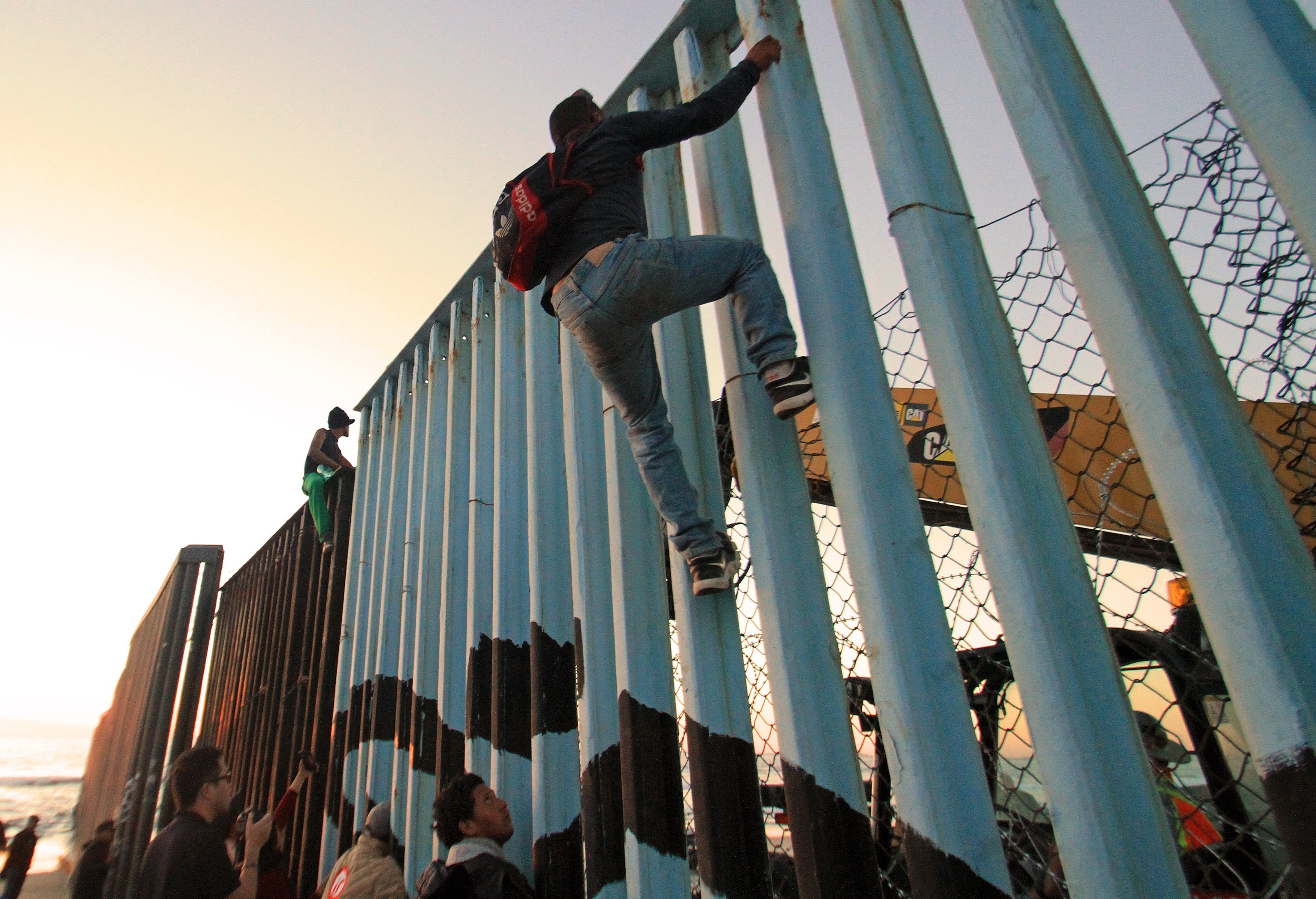 Migrantes de la primera caravana, que salió desde honduras y recorrió el territorio mexicano, comienzan a congregarse en la valla fronteriza de Tijuana. (EFE/Joebeth Terriquez)