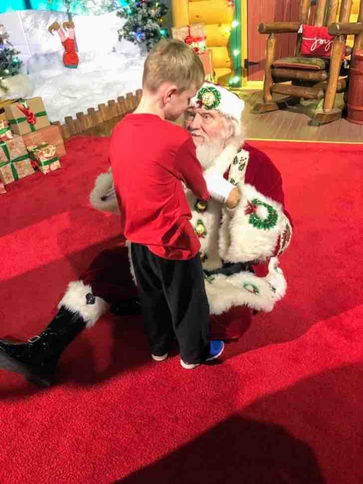 Papa Noel se sienta junto a niño ciego y autista y deja que toque su traje. Él solo quería conocerlo