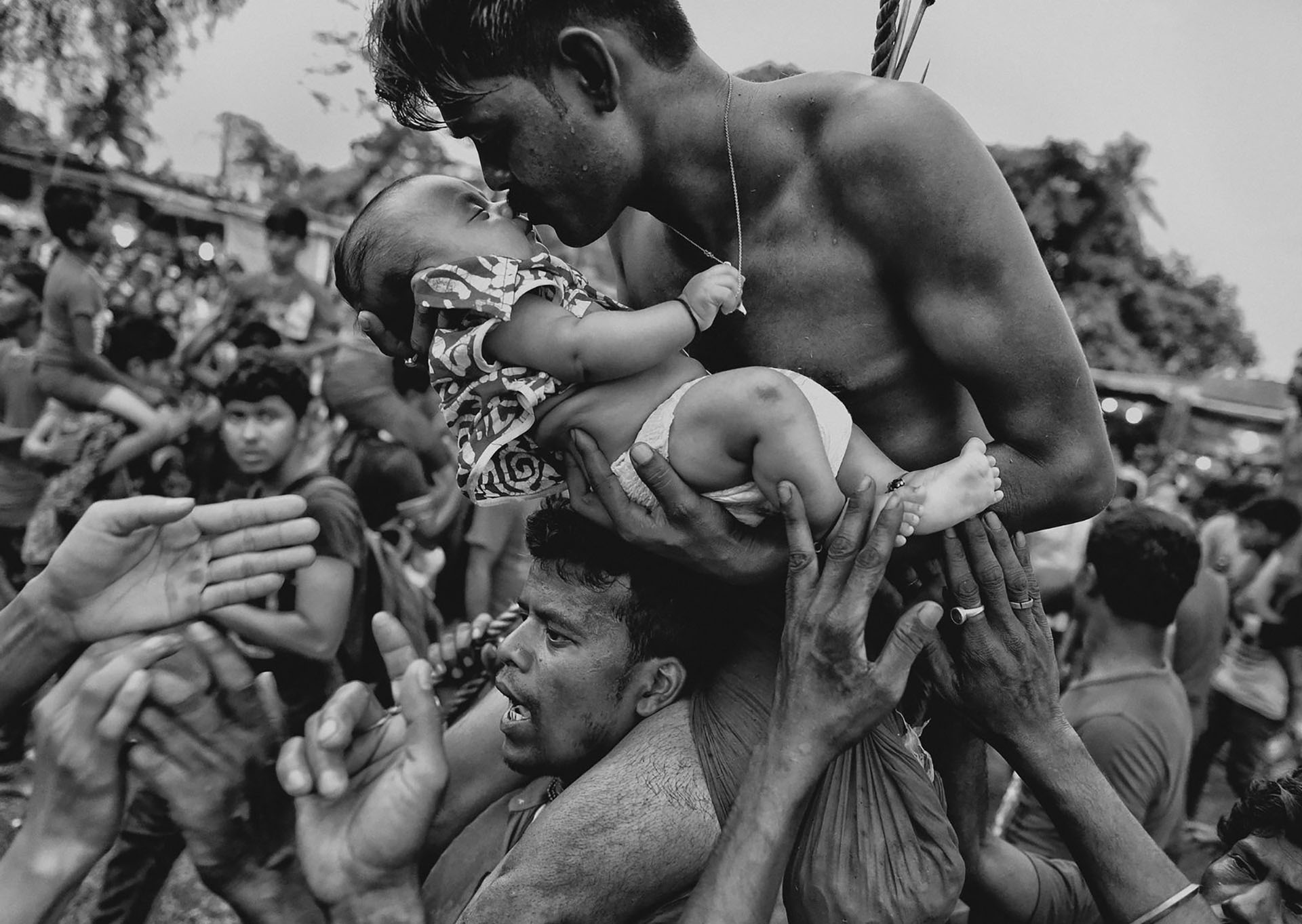 Un hombre hindú besa a un recién nacido durante el festival Charak Puja en India.