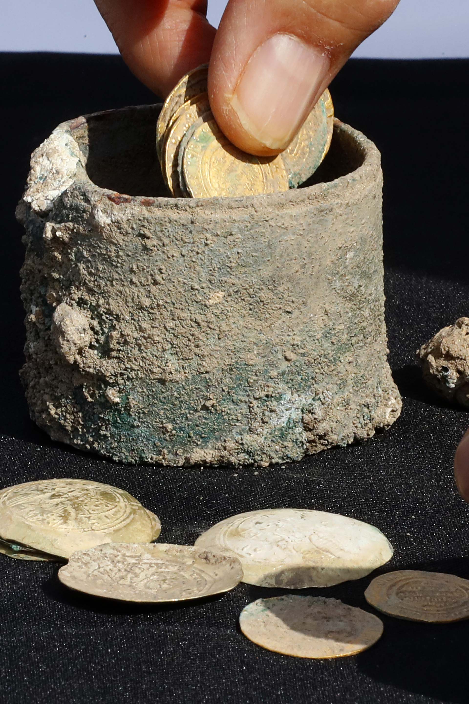 A picture taken on December 3, 2018, shows ancient gold coins and an earring recently uncovered at an excavation site in the Israeli Mediterranean town of Caesarea. – A treasure of 24 rare gold coins consisting of 18 Fatimid dinars, which were the standard local currency during that time (909-1171), as well as six are Byzantine coins, which include five dating to the era of Byzantine Emperor Michael VII Doukas (1071-1078), was recently uncovered in Caesarea. (Photo by JACK GUEZ / AFP)