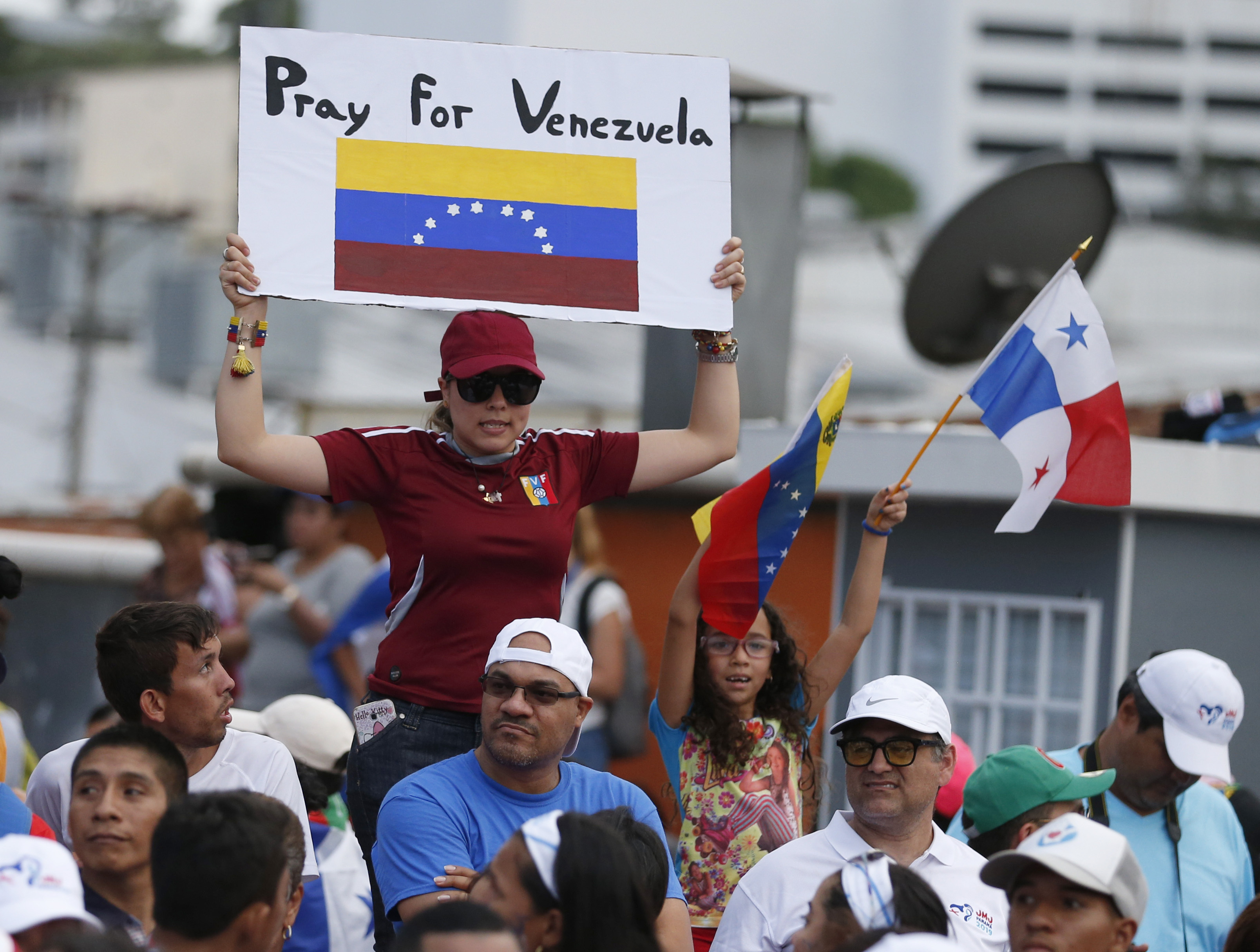 Una mujer levanta una pancarta en que se lee “Pray for Venezuela” (Oren por Venezuela) mientras el papa Francisco se desplaza en el papamóvil por las calles de la Ciudad de Panamá, el miércoles 23 de enero de 2019, tras su arribo al país centroamericano para participar en la Jornada Mundial de la Juventud (AP Foto/ Rebecca Blackwell)