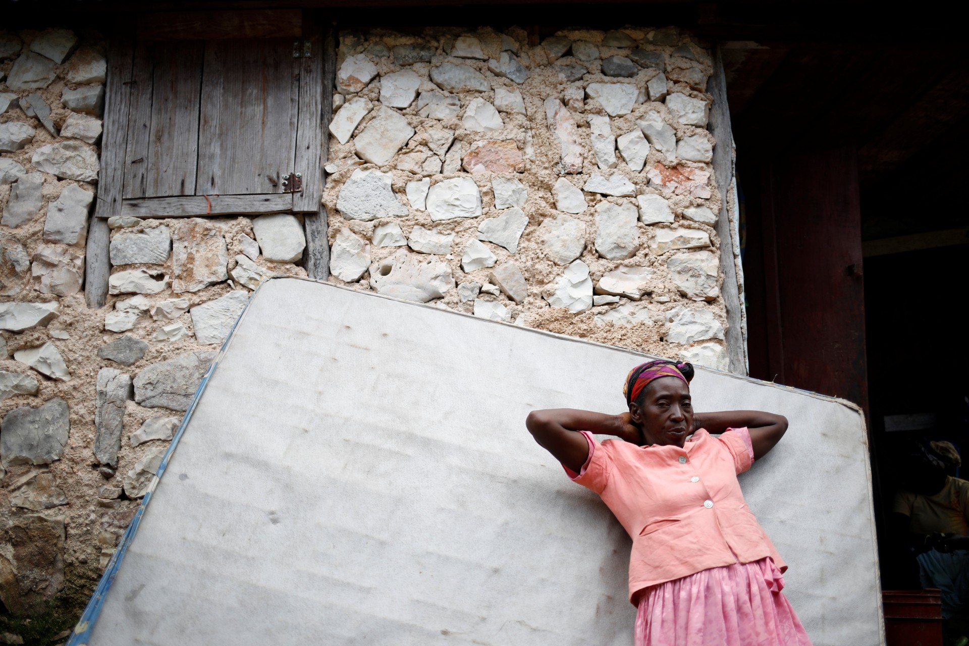 Una mujer se apoya en un colchón de la cama de un vecino que regresó después de años de vivir en República Dominicana, en Boucan Ferdinand, Haití, 10 de octubre de 2018.