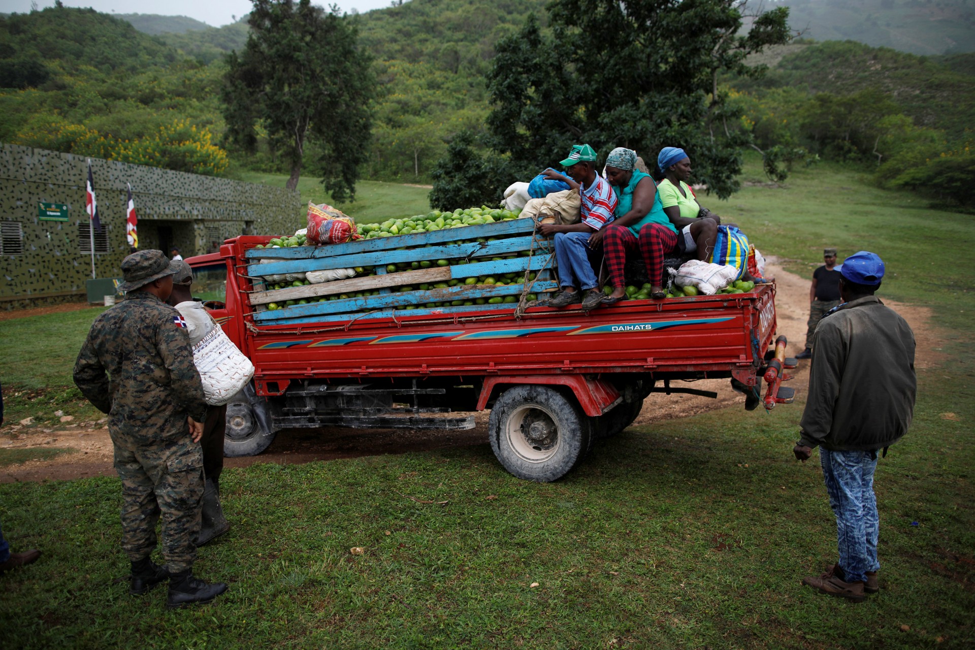 Un miembro de las Fuerzas Armadas Dominicanas mira un camión cargado con aguacates y viajeros en la frontera entre República Dominicana y Haití, en el puesto militar de El Guacate, provincia de Independencia, República Dominicana, 2 de octubre de 2018.