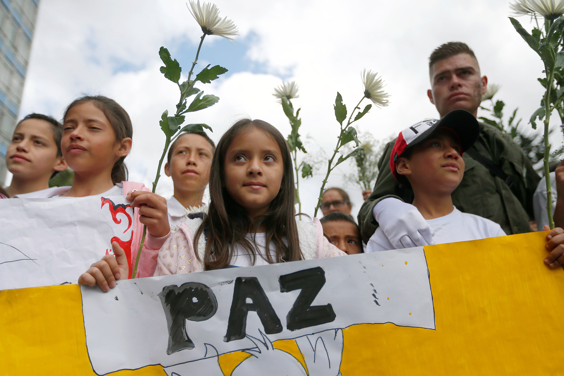 Una niña sostiene un cartel con la palabra “paz”