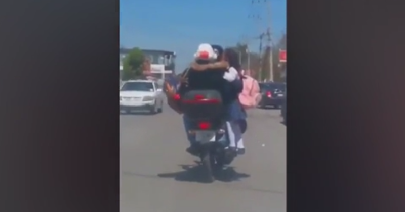 Padres llevan a su hija viajando en el tubo de escape de su moto