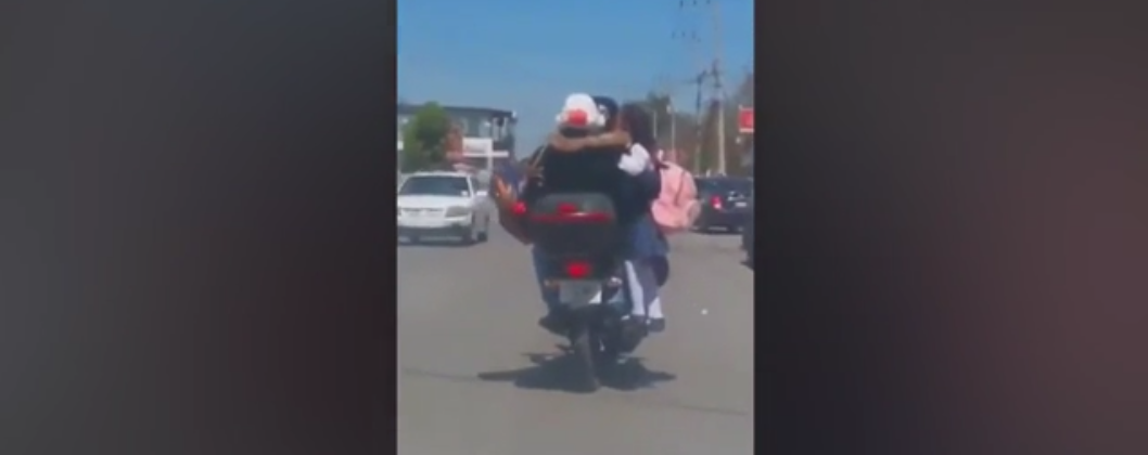 Padres llevan a su hija viajando en el tubo de escape de su moto