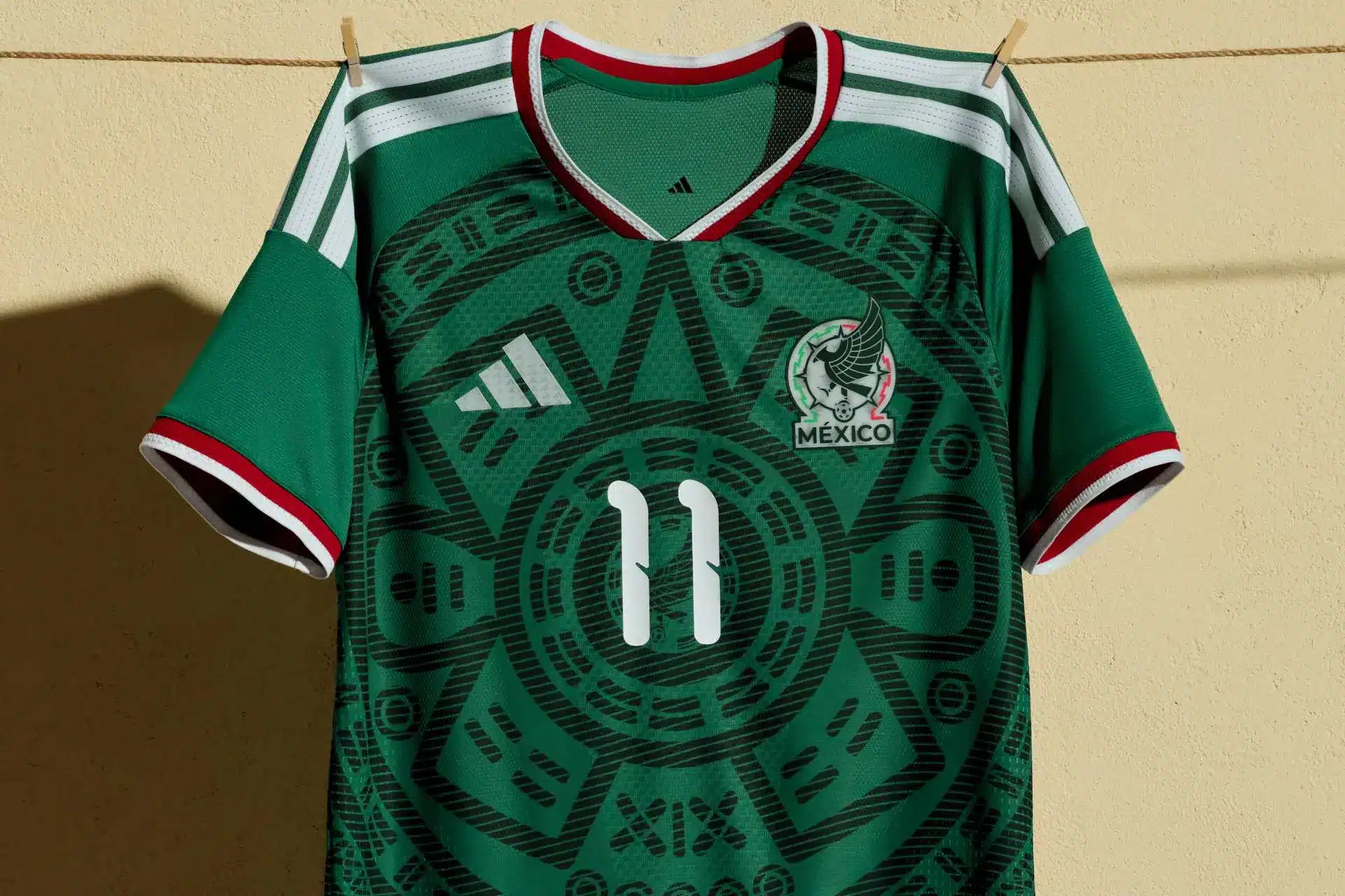 La playera de la selección mexicana rompe récord y lidera ventas mundiales | Green Mexico national soccer team jersey hangs on a clothesline with clothespins displaying the number 11 and Adidas logo