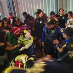 Tragedia en los festejos por el triunfo de México tres personas murieron durante la celebración en el Ángel | Emergency responders in helmets and reflective vests assist a person at the scene of a vehicle accident while onlookers crowd nearby